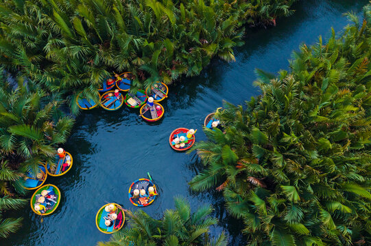 Asian adults enjoying round boat ride through lush greenery in hoi an, vietnam