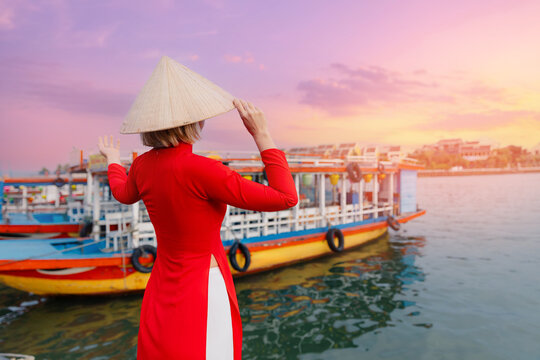 Asian female in traditional red ao dai at hoi an riverside during sunset, vietnam