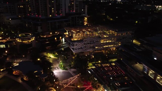 Aerial night view of illuminated modern building surrounded by residential towers in San Pedro Garza Garcia Nuevo Leon Mexico