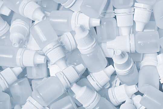 White plastic medical bottles vials for medicinal nose or eye drops as a solid white textured background, medical health concept