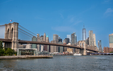 Obraz premium New york, usa august 15,2024. Iconic brooklyn bridge framing lower manhattan skyline and one world trade center across the east river under a clear blue sky