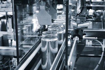 Fototapeta premium factory conveyor moves aluminum cans for beer other carbonated beverages through automated equipment. Metal levers precisely place lids on cans. industrial setting exemplifies precision efficiency.