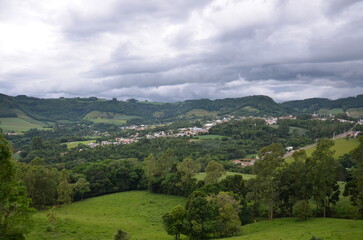 Obraz premium Scenic rural valley with small town and rolling green hills under cloudy sky