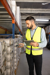 Worker holding digital tablet, scanning barcode with scanner in industrial warehouse. Supply...