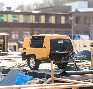 Gothenburg, Sweden - March 06 2026: Portable yellow construction air compressor machine on urban building site.