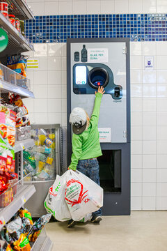 Gothenburg, Sweden - May 04 2014: Child returning plastic bottles at supermarket recycling deposit machine.