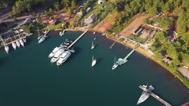 Aerial view of Jesus Beach marina with sailboats and motor yachts docked at pier, Orhaniye, Marmaris, Turkey