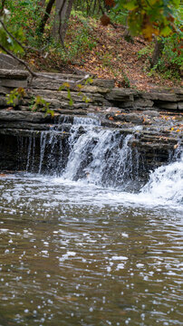 Tilted Cascade: Blurred Waterfall with Foaming Stream and Foreground Branch