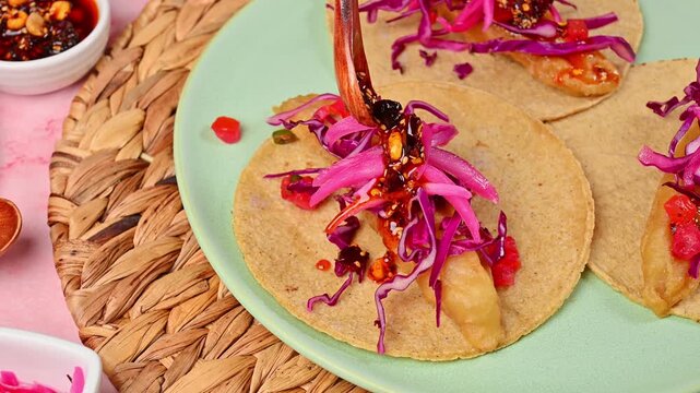 Hands preparing an Ensenada-style fish taco with salsa macha, peanuts and sesame seeds on top