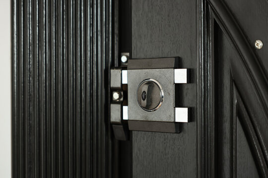 Close-up view of a metal door lock and deadbolt mounted on a dark wood entrance door, conveying security, safety, protection and durable hardware for homes, apartments and commercial properties.