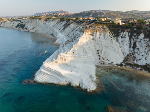 Aerial view of the Stair of the Turks white marl cliffs and turquoise Mediterranean sea with coastal hills in the background in Realmonte, Sicily, Italy.