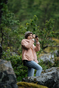 Smiling tourist taking pictures in forest