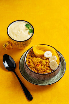 Cup of mango lassi and upma with mango on a table