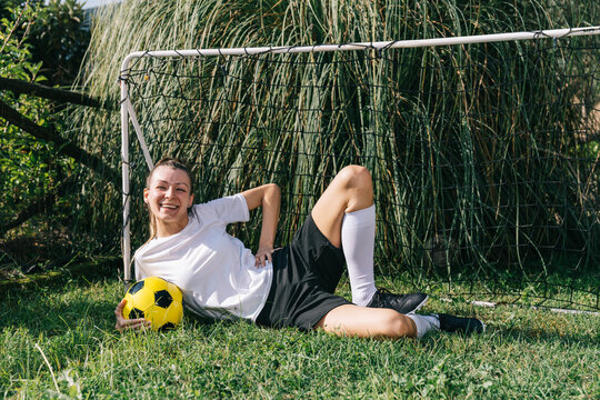 Woman resting with soccer ball in backyard garden