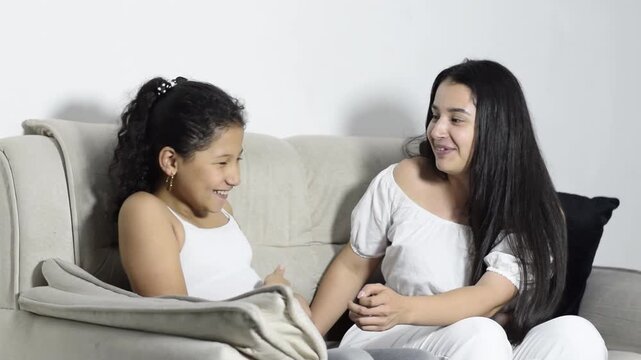 Latina mom chats and laughs with her preteen daughter on a cozy sofa warm family bonding at home now