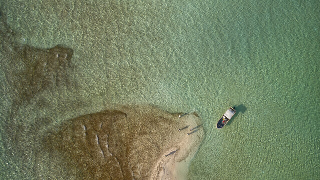 Aerial drone view of a fly fisherman wading the crystal-clear tropical flats of Kiritimati (Christmas Island), Kiribati. A premier destination for saltwater fly fishing, known worldwide for bonefish, 