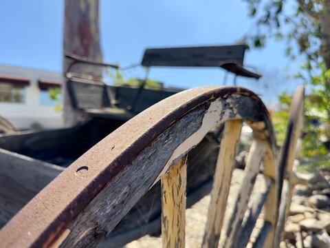 Shallow depth of field shot of a buckboard wagon wheel with the background seat blurred.