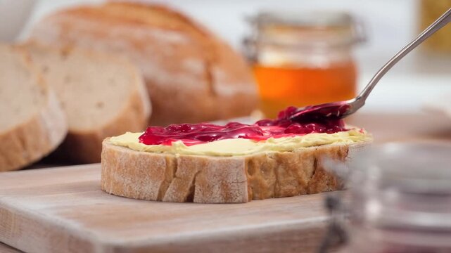 Butter and jam spreading on fresh bread slice close up homemade breakfast, copy space