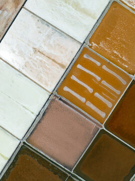 Aerial view of the colorful salt pans of Marsala with rectangular basins of varying shades of white, orange, and brown under bright daylight Marsala, Sicily, Italy.