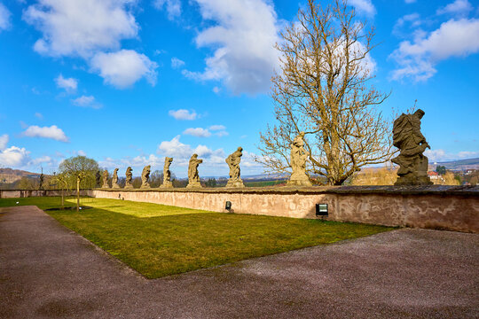 Stone statues lined along historic outdoor pathway under clear blue sky. March 17, 2026 Kuks, Czech Republic