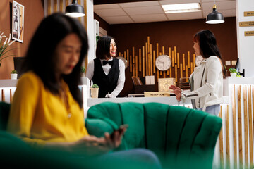 Asian tourists booking room at lavish hotel. Customer making reservation at elegant resort front...