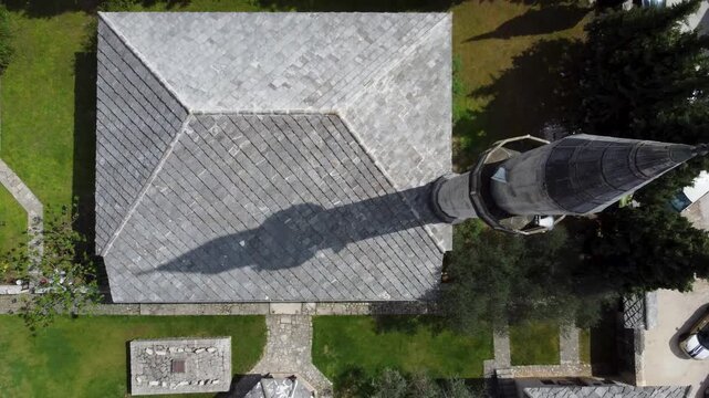 Shadow of mosque minaret on stone roof, drone aerial view. Minaret shadow cast on stone mosque rooftop. A shot of the drone moving away from the mosque.