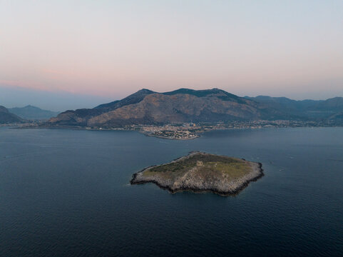 Aerial view of the rocky Isola delle Femmine islet featuring a historic watchtower ruin surrounded by the Mediterranean Sea at dusk in Isola delle Femmine, Sicily, Italy.