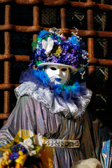 Obraz premium Venice, Italy - February 08, 2026: Elegant masked figure in vibrant costume adorned with flowers and ruffles at Venice Carnival, showcasing intricate details and colorful attire