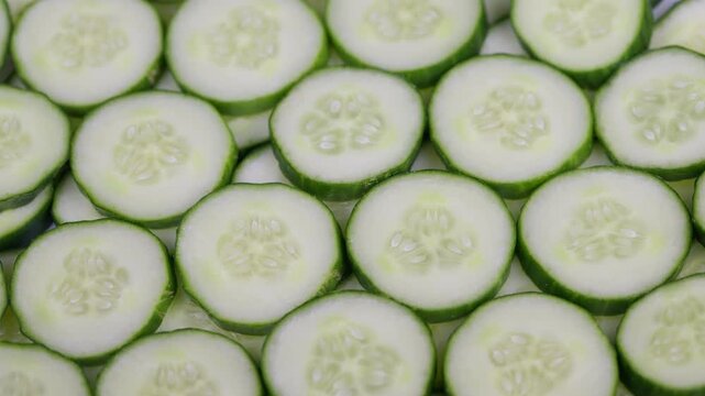 Fresh cucumber slices pattern display. Tightly arranged thin cucumber slices with moist seeds. Close up of fresh green cucumber slices with natural light ambiance
