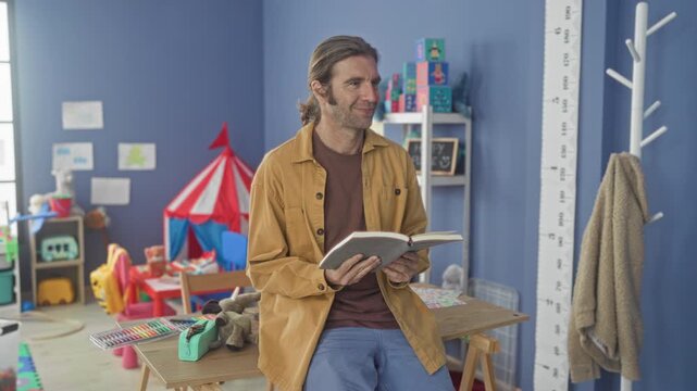 Man holding open book, smiling and reading aloud in a preschool playroom inside a building; nurturing joy.