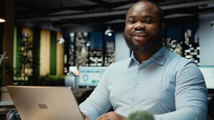 Obraz premium Portrait of black businessman does critical thinking and proofreading files before transcribing data on notebook, sitting in office at night. Documenting important ideas overtime.