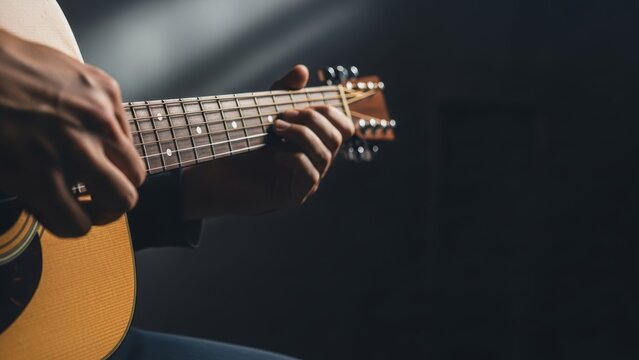 Musician's hands playing chords on an acoustic guitar.