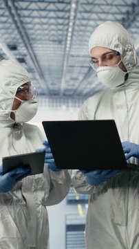 Vertical video EDA engineers in microchip smart factory developing advanced electronics automation process. Experts using simulation software on devices to optimize semiconductor design flow, camera B