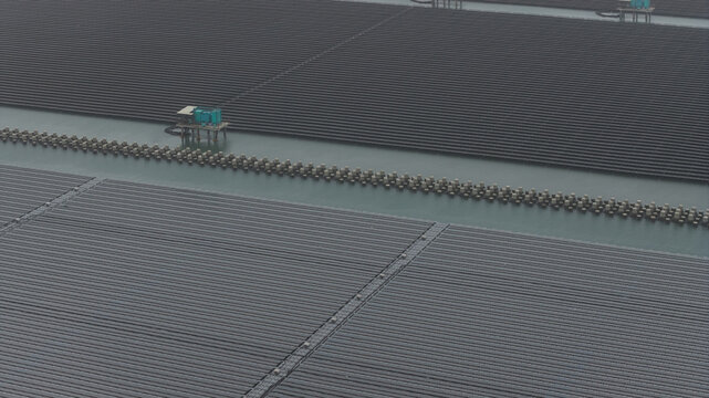 Aerial view of floating solar panels at the Changhua Coastal Industrial Park with technical platforms and concrete barriers on the water surface in Haipu Village, Changhua County, Taiwan.