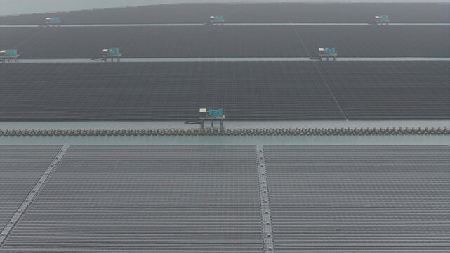 Aerial view of the vast floating solar panel arrays and utility platforms at the Changhua Coastal Industrial Park under a misty sky in Haipu Village, Changhua County, Taiwan.