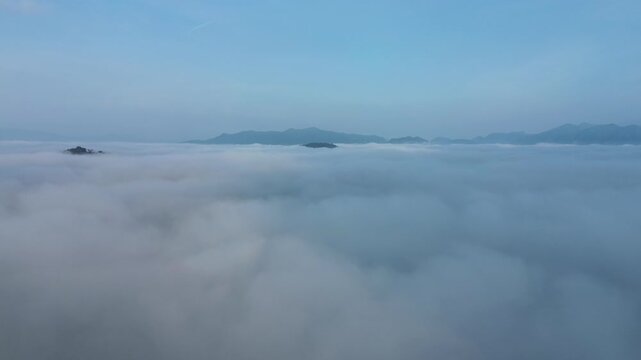 Soaring above a serene sea of morning clouds, mountain peaks emerge in a breathtaking atmospheric