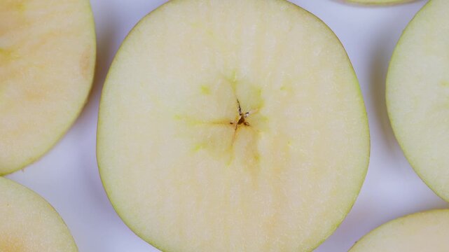 Apple cross section. Studio shot of crisp sliced green apple with dew drops. Minimalist flat lay image showcasing green apple slices with starshaped cores and subtle dew