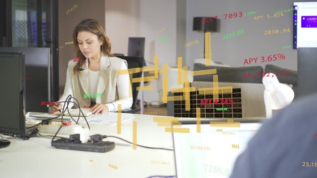 Typing woman wearing blazer analyzing market data as feed starting at desk with colleague, laptop