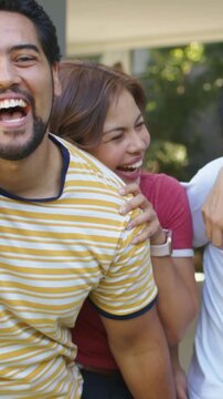 Vertical video: Leaning woman in red ringer tee laughing at porch, drawing friends in, necklace