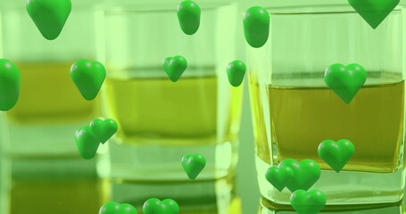 Showing square glass tumbler on reflective table, holding amber liquid and green hearts, copy space © vectorfusionart