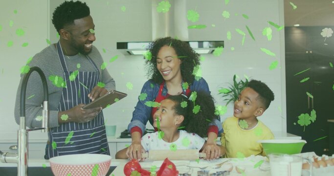 Gathering family preparing food at home kitchen island, parents in aprons, tablet and rolling pin