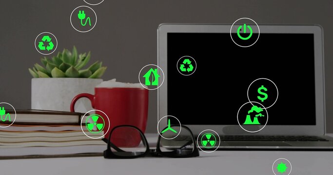 Displaying silver laptop on right of office desk, with books, red mug, green icons, copy space