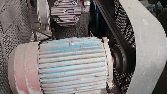 Old industrial electric motor with belt drive system in workshop