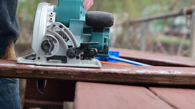 Cutting deck boards with circular saw, authentic real time video selective focus, work outside, working on deck wood