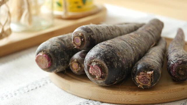 Fresh whole purple carrots on wooden cutting board with dynamic close up cinematic footage.