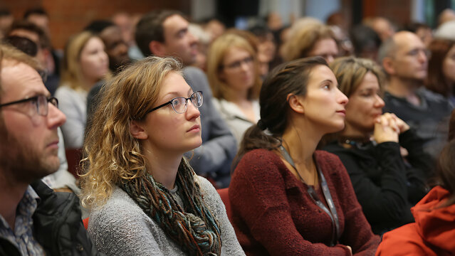 Attentive Woman with Glasses and Diverse Audience Engaged in Conference Learning