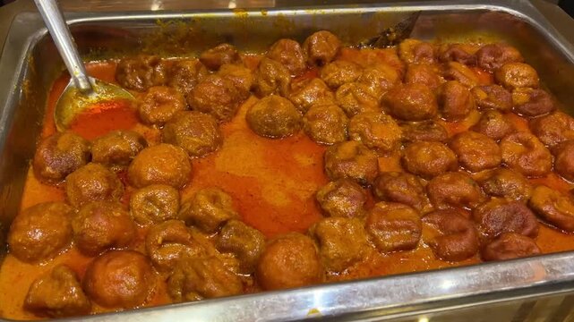 Authentic Marwari-style Malai Kofta: Fried paneer and potato dumplings simmered in a rich, velvety cashew and cream gravy at a grand Indian wedding.