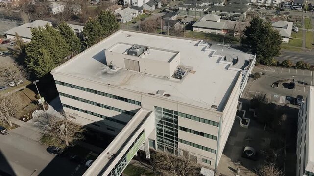 Up view of a flat-roof modern building in a suburban area, with surrounding streets and houses