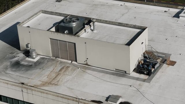 view of a flat roof commercial building with rooftop equipment, captured from above in daylight. 