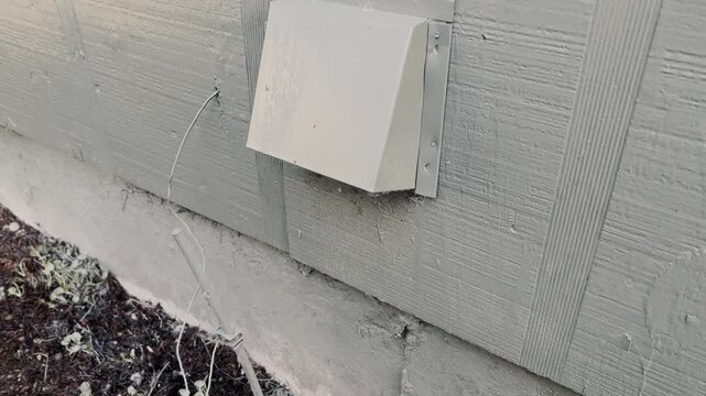 Exterior vent cover mounted on a building wall, close up, ventilation and utility detail.